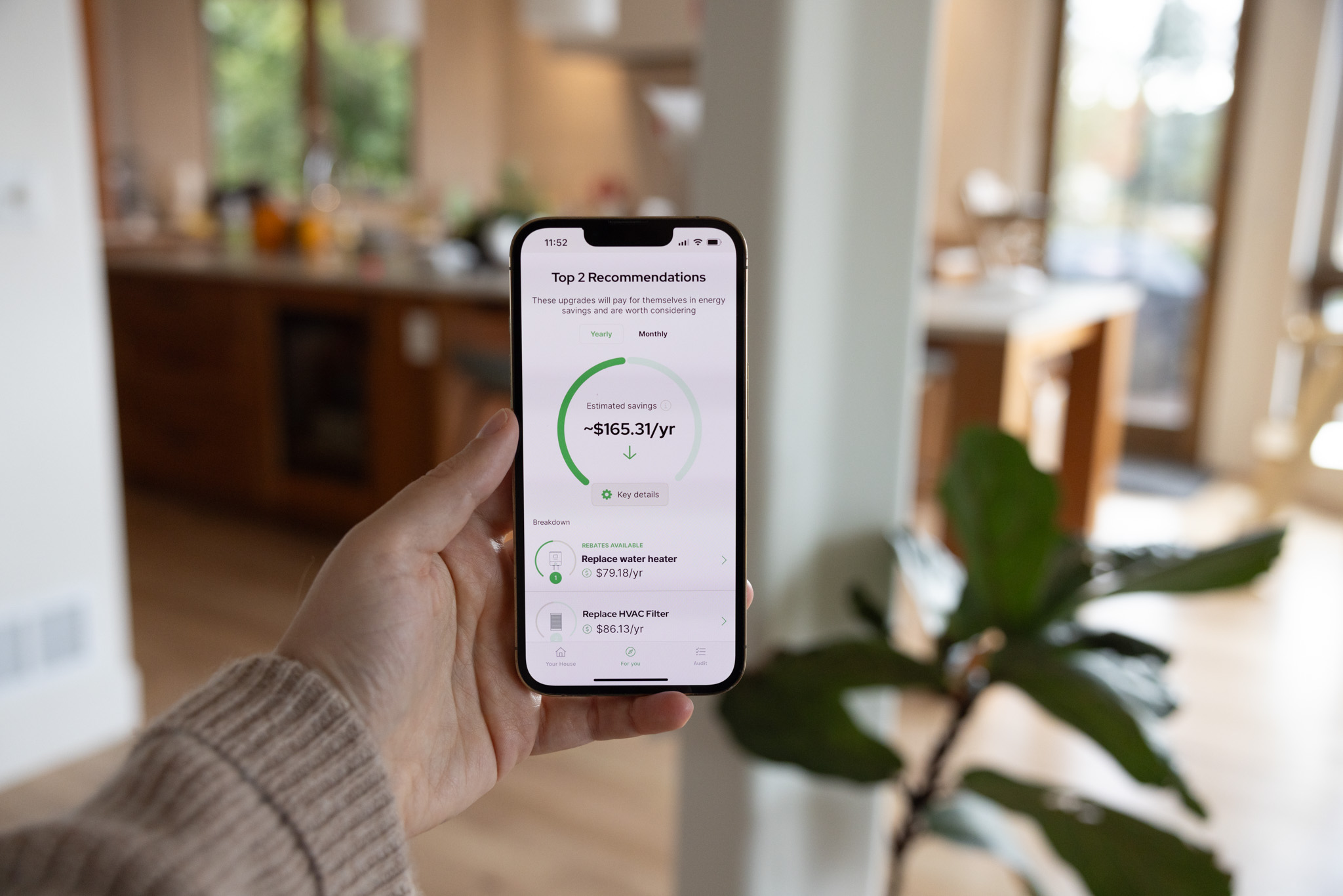 Hand holding phone and showing HomeBoost recommendations and estimated savings